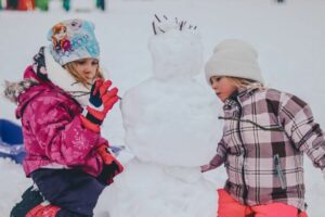 2 kids building a snowman