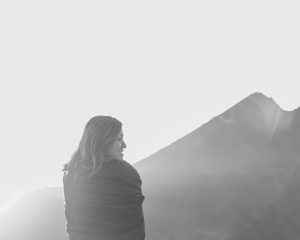 a photo of a happy woman looking at a mountain