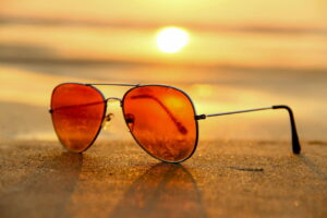 closeup of orange sunglasses with the sun setting behind them