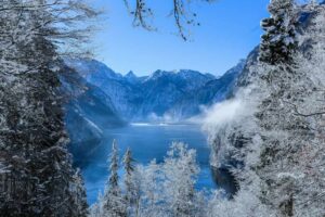 winter mountain scene with snow on trees around a lake